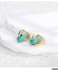 Detail of vintage gold hoop earrings with turquoise stone beads on a white pedestal