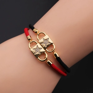 Detail of star-patterned lock pendants on red and black braided cord bracelets