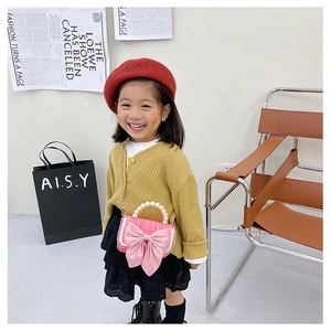 Girl wearing mustard cardigan and pink plaid crossbody bag with large satin bow