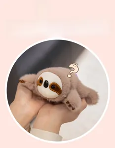 Close-up of a small plush sloth magnet toy held in hands to show its palm-sized scale