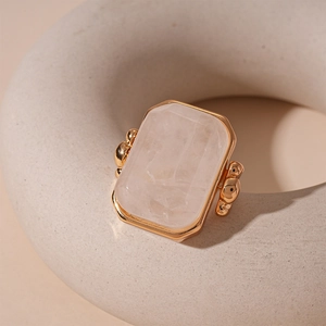 Detail of a square pink natural stone ring with gold metal setting and beaded accents