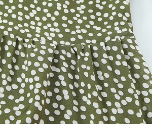 Vue macro de la robe à pois vert olive montrant les plis à la taille et les coutures