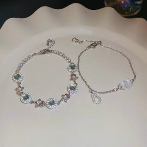 Detail of silver bracelets with green cat eye stones, butterfly and zircon gourd pendants