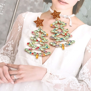 Detailed macro view of gold-tone Christmas tree earrings with sparkling green and multi-color crystals