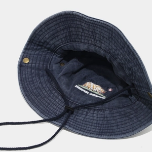 Gros plan sur la broderie d'ours et le cordon réglable du chapeau bob en denim