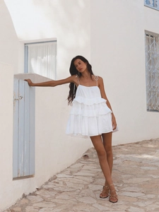 Detail of layered ruffles on a white summer mini dress with tiered cotton fabric