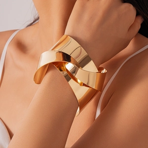 Detailed view of wide gold knotted bangle with polished mirror finish on arm