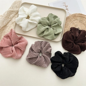 Set of pleated satin scrunchies in various pastel colors on a decorative tray