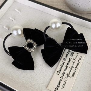 Macro shot of black velvet bows with rhinestones and large pearls on a display tray