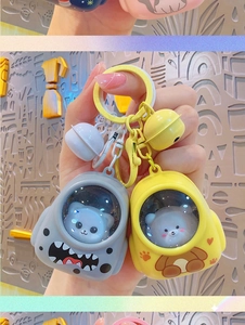 Close-up of cute cartoon space capsule keychains featuring a grey cat and yellow bear