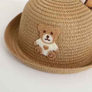 Close-up of fine straw weave and cute knitted bear patch on the children summer hat
