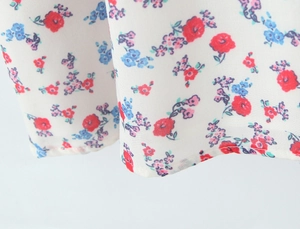 Close-up of floral embroidery on white fabric with detailed hem stitching on the dress