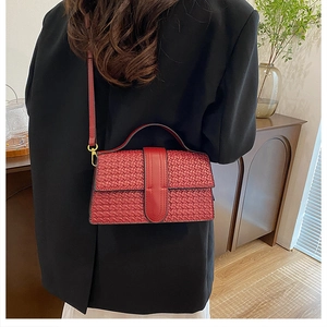 Detail shot of the red woven texture and metal hook on a crossbody square bag