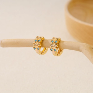Macro detail of gold-plated hoop earrings with turquoise stones and cubic zirconia