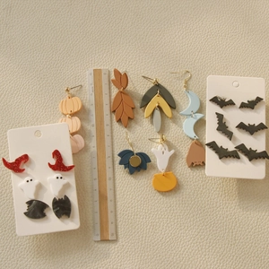 Halloween earring set with pumpkin, ghost, and bat charms, including ruler for scale