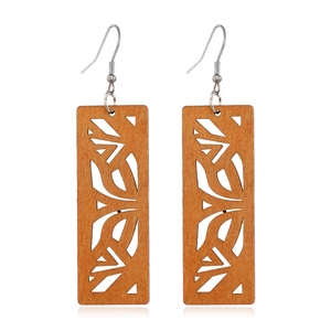 Macro shot of rectangular hollowed-out brown wood earrings with smooth natural textures