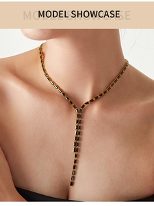 Détail d'un collier en Y avec pierres noires rectangulaires porté par un modèle