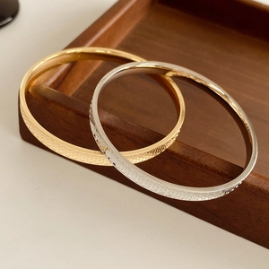 Detailed view of gold and silver textured concave bangles on a wooden tray
