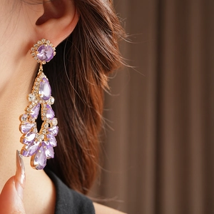 Close-up of elegant gold drop earrings with purple crystal rhinestones on model