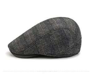 Seitenansicht der Retro-Karo-Baskenmütze mit blau-braunem Wollstoff und schwarzem Lederschirm