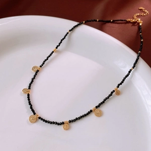 Detailed close-up of round crystal beaded necklace with black stones and gold pendant