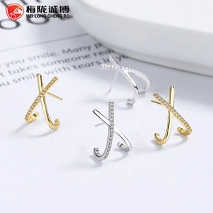 Macro view of gold and silver cross-shaped 925 sterling silver earrings with zircons