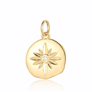 Detailed macro view of a round gold pendant with carved star and clear gemstone inlay