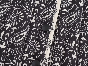 Dettaglio ravvicinato del motivo paisley bianco e nero con trapuntatura e bottoni