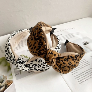 Leopard print bow headbands in brown and white fabric on a lifestyle magazine backdrop