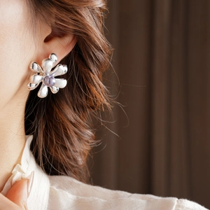 Detail of silver flower earrings with purple center bead worn by a fashion model