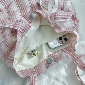 Detail of pink plaid tote bag interior with lace trim and magnetic closure capacity