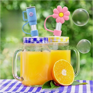 Pink daisy and blue mini jug silicone straw covers shown in a fresh picnic setting