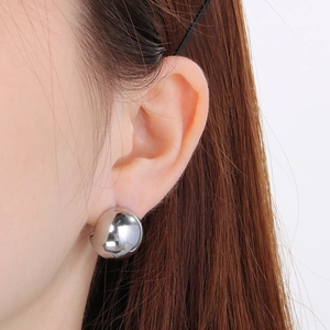 Close-up of minimalist silver spherical stud earrings with a high-polished mirror finish