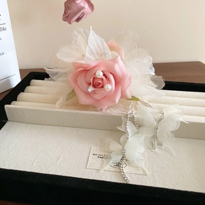 Détail d'une pince à fleurs en tissu rose avec perles et pompons papillon en tulle