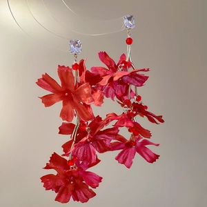 Detail of red fabric flower earrings with crystal tassels and silver needles in close-up