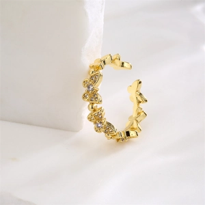 Detailed close-up of golden butterfly ring with sparkling zircons on white silk