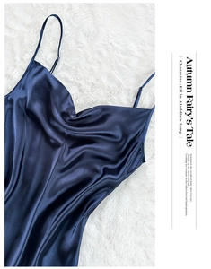 Flat lay of a luxury dark blue satin nightgown with thin straps on a white fur background