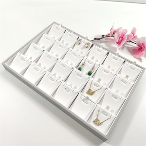 Detail view of 24-slot jewelry display tray with grey frame and white velvet padding