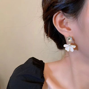 Detail of elegant gold flower earring with crystal and pearls on model for a soft look