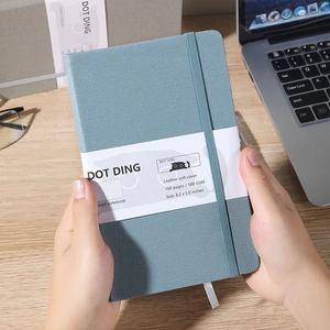 Blue cloth dotted journal with 160 pages of 100 GSM paper in a hand-held office setting