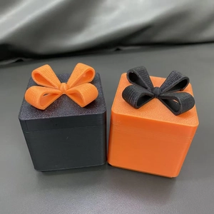 Dettaglio di scatole regalo stampate in 3D con fiocchi in nero e arancione