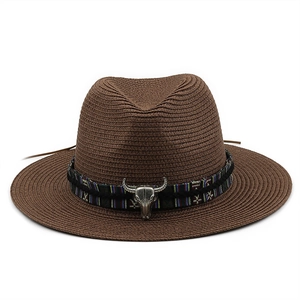 Brown straw cowboy hat with wide brim, ethnic band and metal bull skull ornament