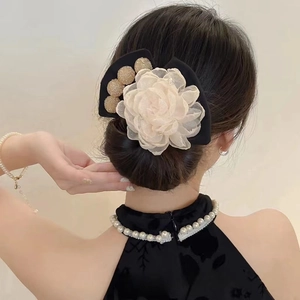 Pince à cheveux fleur camélia beige élégante avec nœud noir sur une coiffure en chignon