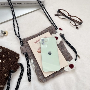 Detail of plush crossbody bag featuring sheepskin texture and floral knot rope strap