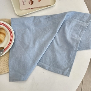 Close-up of light blue linen placemat featuring a flat stitched edge and woven texture