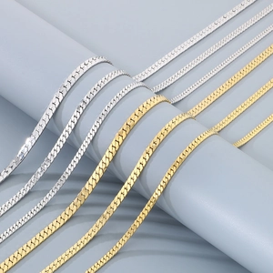 Detailed close-up of flat Cuban link necklaces in polished gold and silver finishes