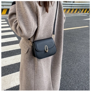 Close-up of black vintage crossbody bag with gold U-shaped metal lock and matte texture