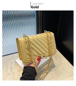 Detail of gold shoulder bag with V-shaped quilting and square metal twist-lock