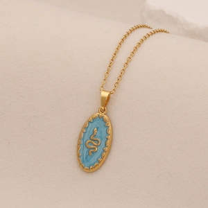 Detail view of gold necklace featuring a blue oval pendant with a golden snake motif