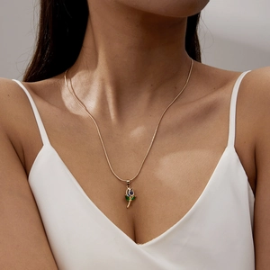 Elegant gold tulip necklace with blue teardrop crystal worn by a model on silk